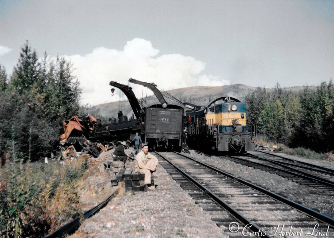 The aftermath of locomotive 801 with a gravel train running into the back half of a North bound freight train at the South end of the Nenana Yard. All the gore is documented elsewhere. No one died but 801 and a nearly brand new Pacific Foundry steel caboose were destroyed. That strange looking ALCO is an RSD1 converted to four wheel trucks. The high arch narrow cab gives it away as a military surplus locomotive built for close clearances.