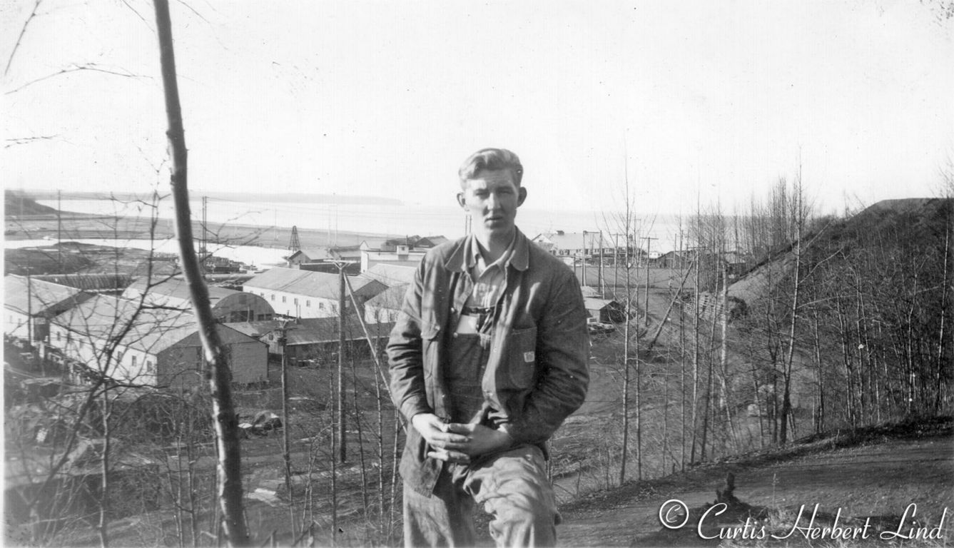 Unidentified young man on the hill side trail going up Government Hill at Anchorage. The Emard Cannery is just over his left shoulder. The photo is post war as there is a quonset hut above the building in the railroad yard. Ship Creek meanders among the mud flats out to Cook Inlet.Anchorage from Government Hill. The warehouses on the left are “Loctwall” prefabricated Warehouses 40’ x 100’ erected in 1949.  Erecting Instructions for the warehouses was received in the office of the Chief Engineer on December 2, 1948.Curt Lind in photo.