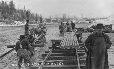 Laying first rails of new U.S. railroad at Ship Creek